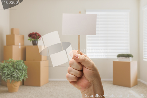 Image of Hand Holding Blank Sign in Empty Room with Packed Moving Boxes