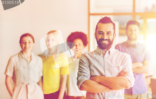 Image of happy young man over creative team in office