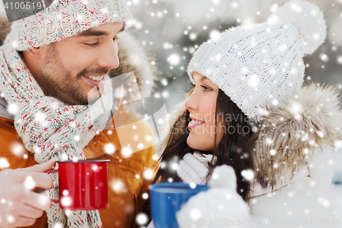 Image of happy couple with tea cups over winter landscape