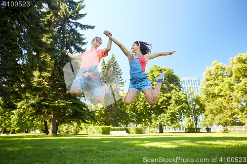 Image of happy teenage couple jumping at summer park