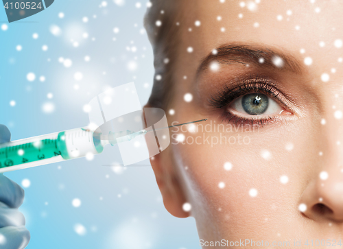 Image of close up of woman face and syringe over snow