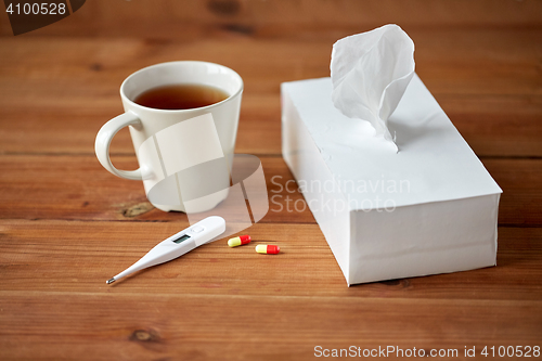 Image of cup of tea, paper wipes and thermometer with pills