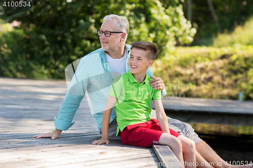 Image of grandfather and grandson sitting on river berth