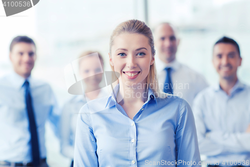 Image of smiling businesswoman with colleagues in office