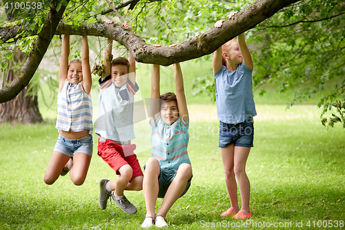 Image of happy kids hanging on tree in summer park