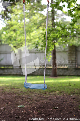 Image of empty wooden swing hanging in summer garden