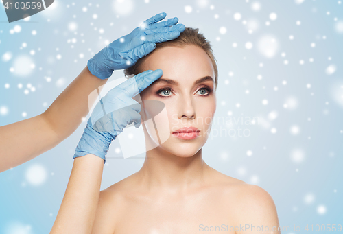 Image of surgeon or beautician hands touching woman face