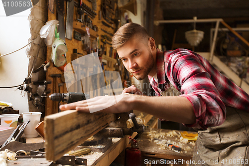 Image of carpenter working with wood plank at workshop