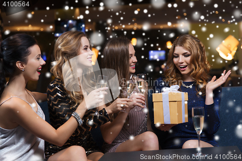 Image of happy women with champagne and gift at night club