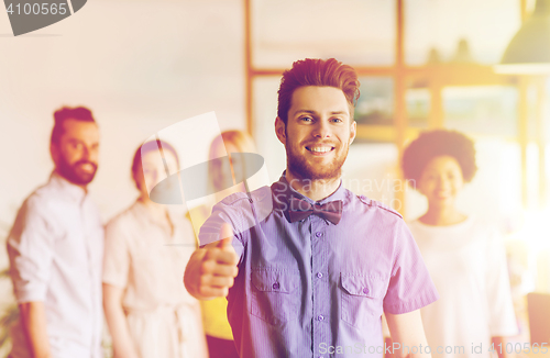 Image of happy man showing thumbs up over team in office