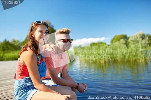 Image of happy teenage couple sitting on river berth