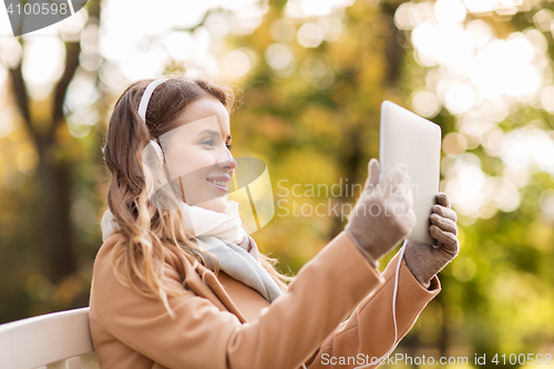 Image of woman with tablet pc and headphones in autumn park