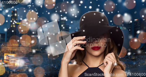 Image of beautiful woman in black hat over night city