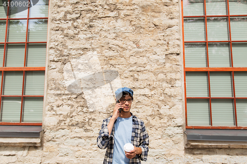 Image of man with smartphone drinking coffee on city street