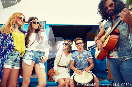 Image of happy hippie friends playing music over minivan