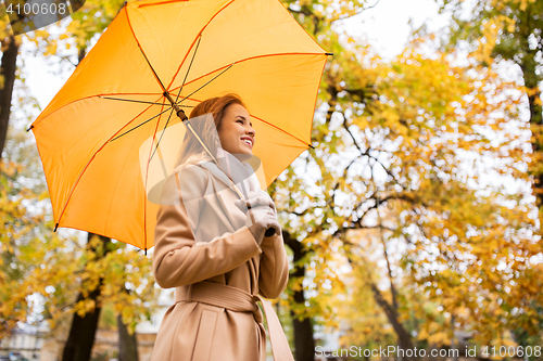 Image of happy woman with umbrella walking in autumn park