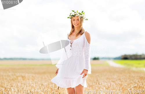 Image of happy young woman in flower wreath on cereal field