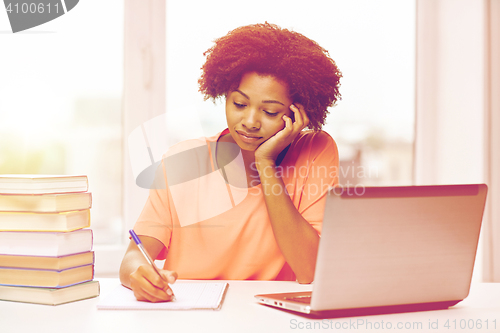 Image of bored african american woman doing homework home