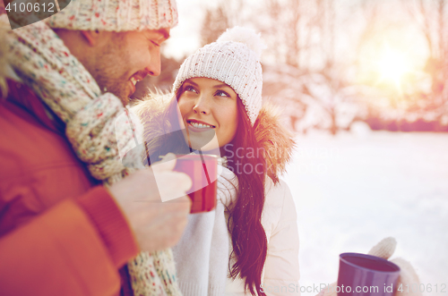 Image of happy couple with tea cups over winter landscape