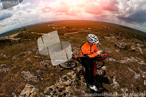 Image of Young Male Cyclist Talking On Cell Phone