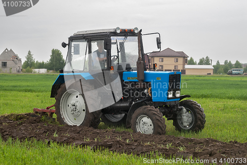 Image of Tractor operator plows the site in rain