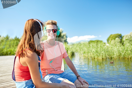 Image of happy teenage couple with earphones on river berth