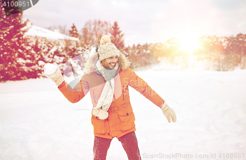 Image of happy young man playing snowballs in winter