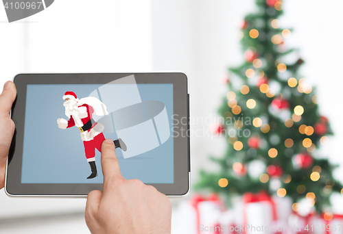Image of close up of hands with santa claus on tablet pc