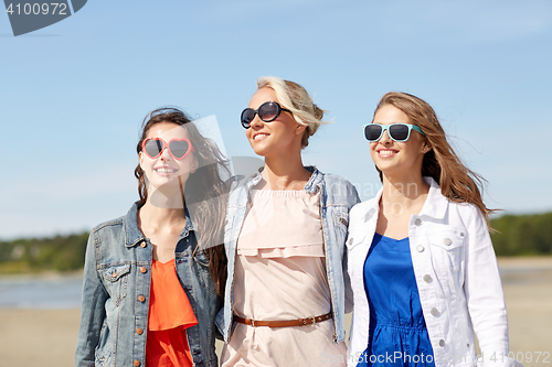 Image of group of smiling women in sunglasses on beach