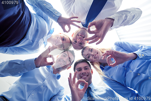 Image of smiling group of businesspeople standing in circle