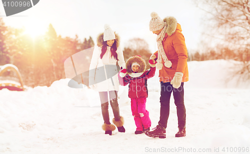 Image of happy family in winter clothes walking outdoors