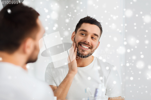 Image of happy young man looking to mirror at home bathroom