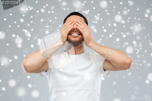 Image of smiling man closing his eyes over snow background