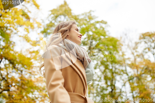 Image of beautiful happy young woman smiling in autumn park