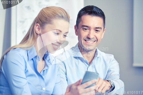 Image of smiling businesspeople with smartphones in office
