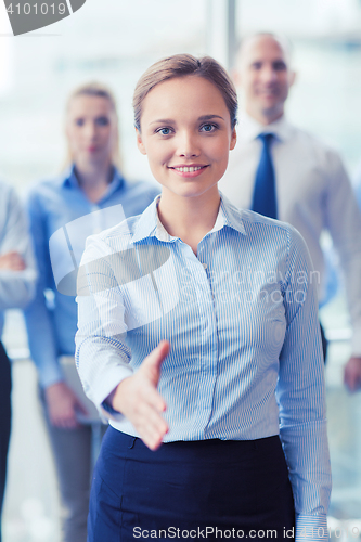 Image of smiling businesswoman making handshake in office