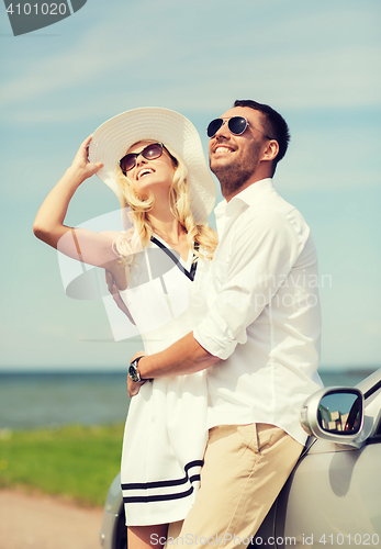 Image of happy man and woman hugging near car at sea