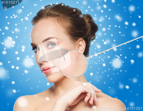 Image of beautiful woman with magnifier on face over snow