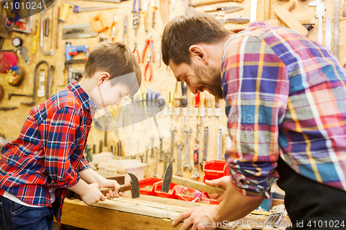 Image of father and son with hammer working at workshop