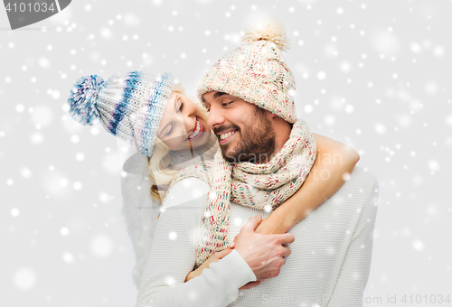 Image of smiling couple in winter clothes hugging over snow