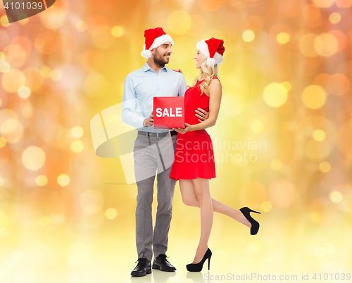 Image of happy couple in santa hats with red sale sign