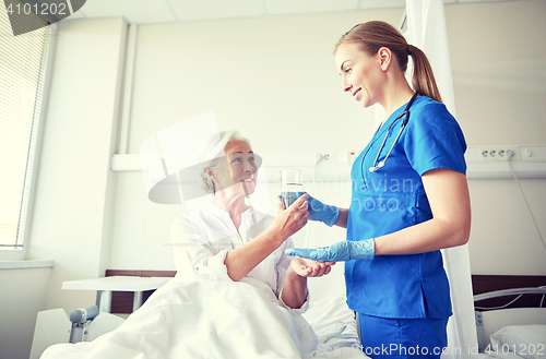 Image of nurse giving medicine to senior woman at hospital