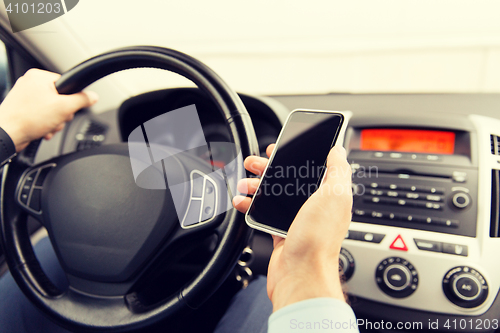 Image of close up of man hand with smartphone driving car