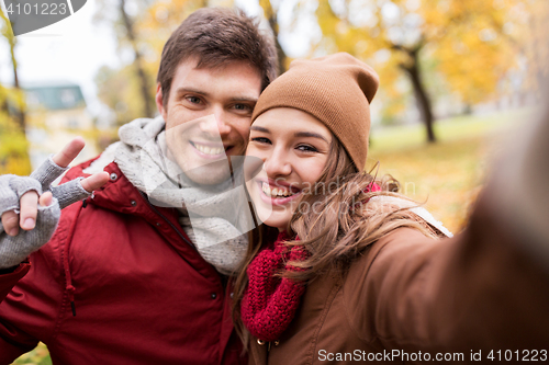 Image of happy young couple taking selfie in autumn park