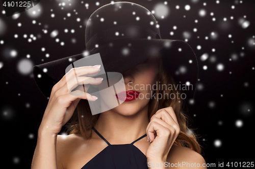 Image of beautiful woman in black hat over snow