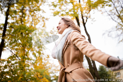 Image of beautiful happy young woman walking in autumn park