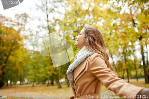 Image of beautiful happy young woman walking in autumn park
