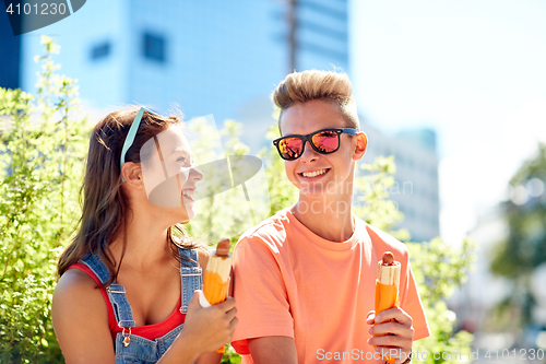 Image of happy teenage couple eating hot dogs in city