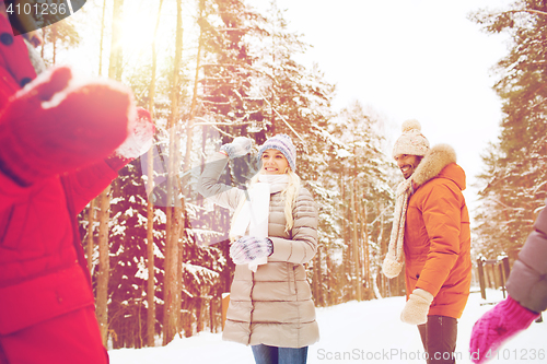 Image of happy friends playing snowball in winter forest