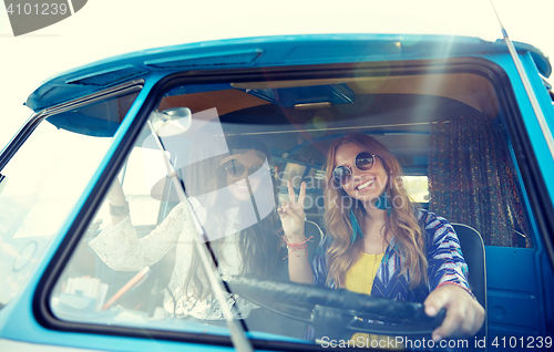 Image of smiling young hippie women driving minivan car